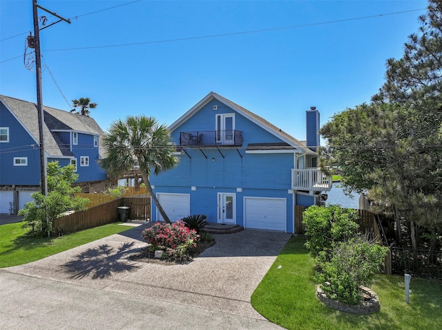 beach home featuring a chimney, fence, a balcony, a garage, and driveway