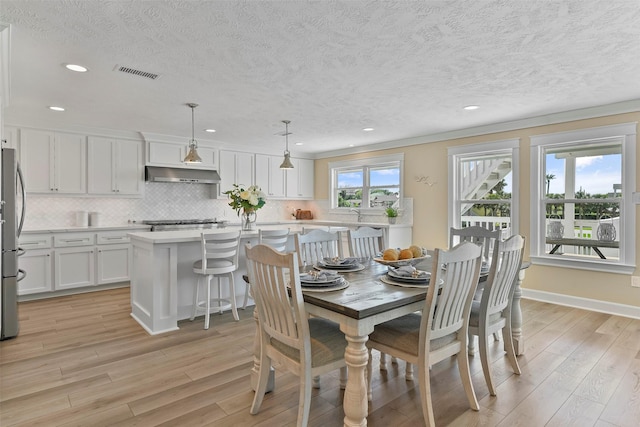 dining area with a textured ceiling, recessed lighting, visible vents, baseboards, and light wood-style floors