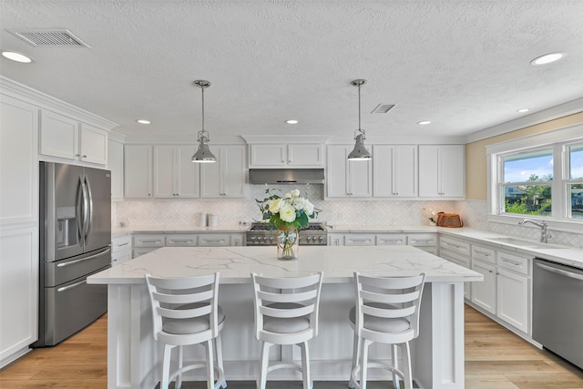 kitchen featuring extractor fan, a kitchen island, a sink, visible vents, and appliances with stainless steel finishes