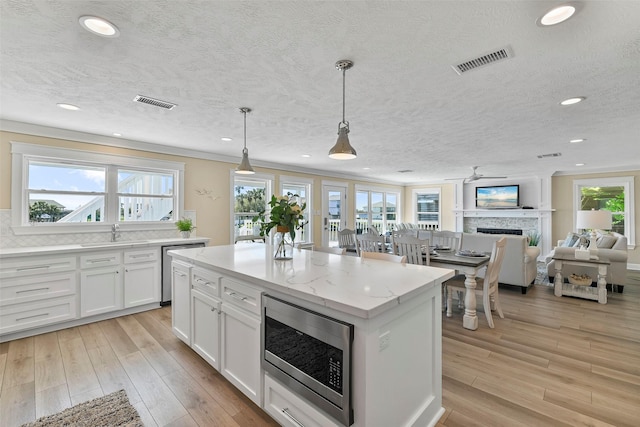 kitchen with light wood finished floors, visible vents, white cabinets, appliances with stainless steel finishes, and a fireplace