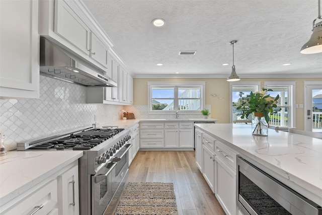 kitchen with tasteful backsplash, visible vents, appliances with stainless steel finishes, white cabinets, and under cabinet range hood