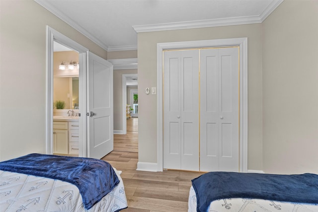 bedroom featuring crown molding, light wood finished floors, a closet, a sink, and baseboards