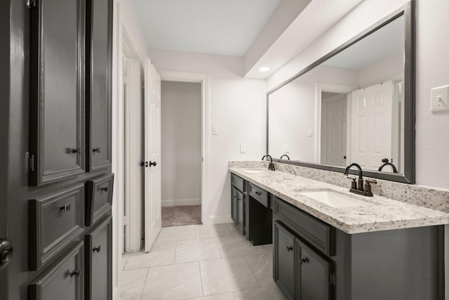 full bathroom featuring double vanity, baseboards, tile patterned floors, and a sink