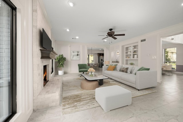 living room featuring built in features, visible vents, ornamental molding, a brick fireplace, and marble finish floor