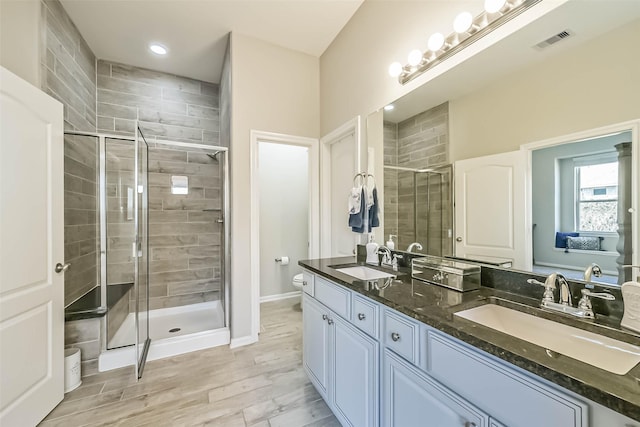 bathroom with toilet, a sink, visible vents, and a shower stall