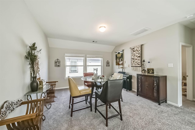 carpeted dining area with lofted ceiling, visible vents, and baseboards