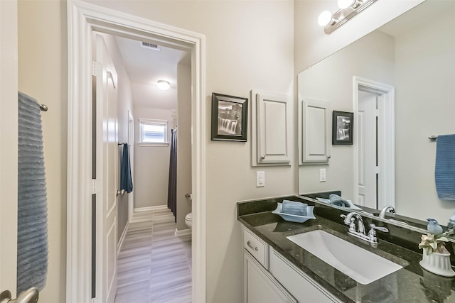 full bathroom featuring toilet, baseboards, visible vents, and vanity