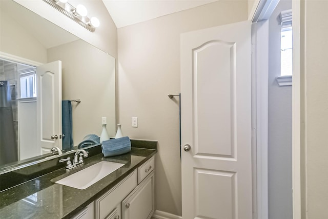 bathroom with lofted ceiling, a wealth of natural light, and vanity