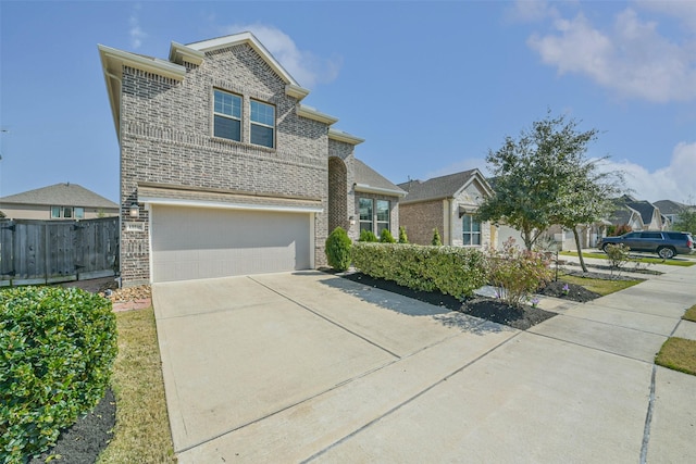 view of front facade featuring a garage, concrete driveway, brick siding, and fence