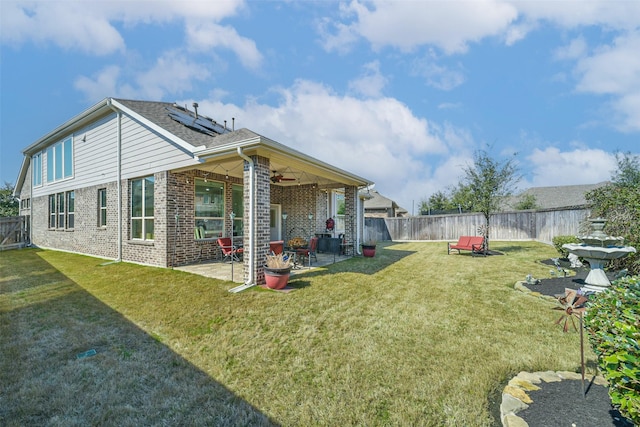 rear view of house featuring brick siding, a lawn, a patio area, ceiling fan, and a fenced backyard