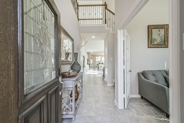 entrance foyer featuring a high ceiling, baseboards, and light tile patterned flooring