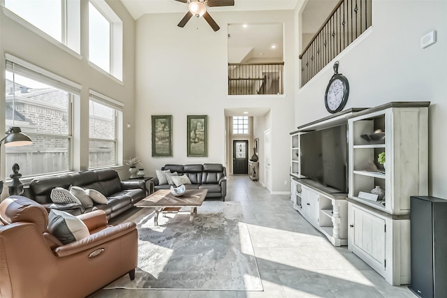 living room featuring baseboards, ceiling fan, and a high ceiling