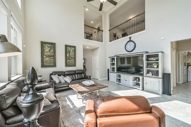 living room featuring a towering ceiling, a ceiling fan, and baseboards