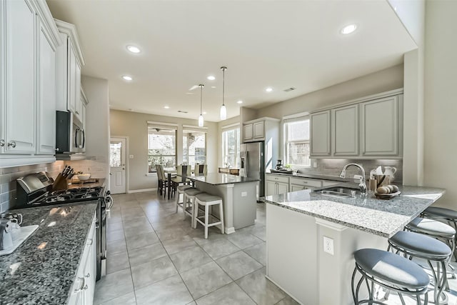 kitchen with light tile patterned floors, a breakfast bar, stainless steel appliances, a sink, and recessed lighting