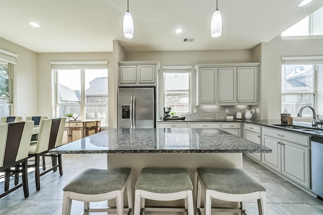 kitchen featuring appliances with stainless steel finishes, backsplash, a sink, and a wealth of natural light