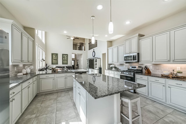 kitchen with tasteful backsplash, appliances with stainless steel finishes, open floor plan, a center island, and light tile patterned flooring