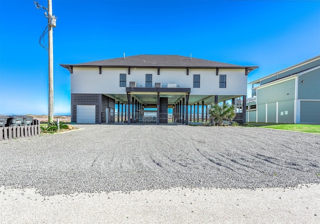 636 Villa Dr, Crystal Beach, TX 77650 - back of house with stairs, a carport, gravel driveway, and an attached garage