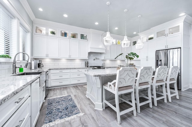 636 Villa Dr, Crystal Beach, TX 77650 - kitchen with crown molding, premium range hood, a kitchen bar, white cabinetry, and a sink