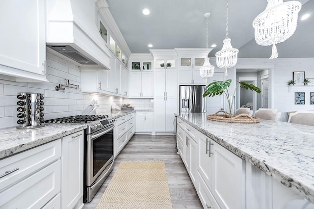 636 Villa Dr, Crystal Beach, TX 77650 - kitchen featuring stainless steel appliances, tasteful backsplash, custom range hood, white cabinets, and light wood-type flooring