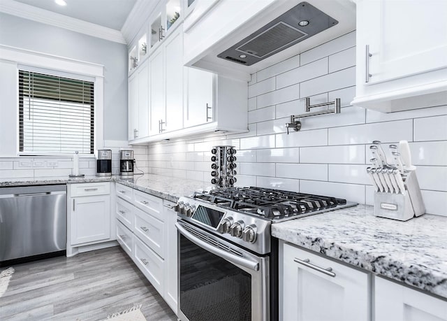 636 Villa Dr, Crystal Beach, TX 77650 - kitchen with white cabinets, appliances with stainless steel finishes, ventilation hood, crown molding, and backsplash