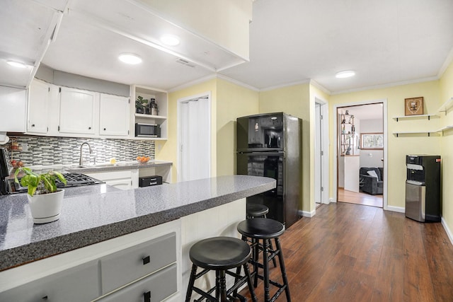 kitchen with cooktop, decorative backsplash, dark wood-type flooring, freestanding refrigerator, and ornamental molding