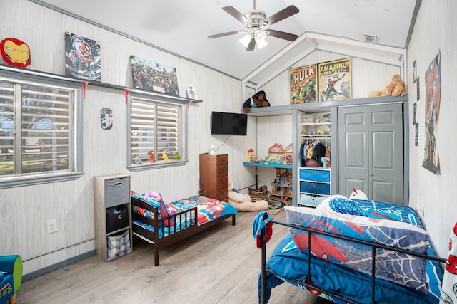 bedroom with visible vents, vaulted ceiling, wood walls, and wood finished floors