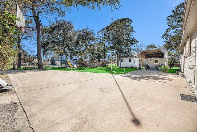 exterior space featuring a carport, an outdoor structure, a playground, and concrete driveway