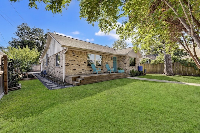 ranch-style home with board and batten siding, a fenced backyard, brick siding, and a front lawn