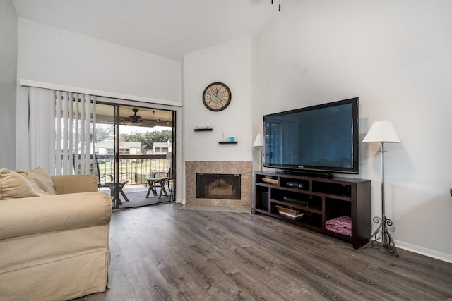 living area with a high ceiling, a premium fireplace, wood finished floors, and baseboards