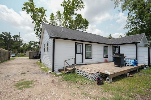 back of house featuring a shingled roof and a wooden deck