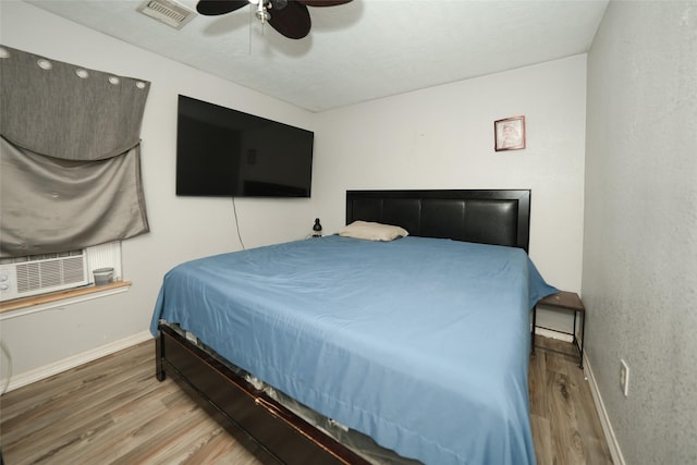 bedroom featuring a ceiling fan, baseboards, visible vents, and wood finished floors