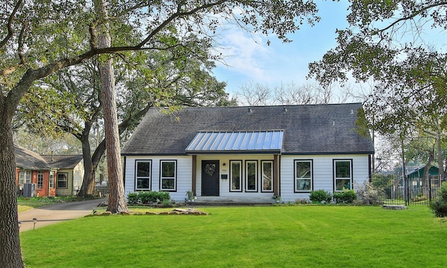 view of front of home featuring metal roof, a front yard, fence, and central air condition unit