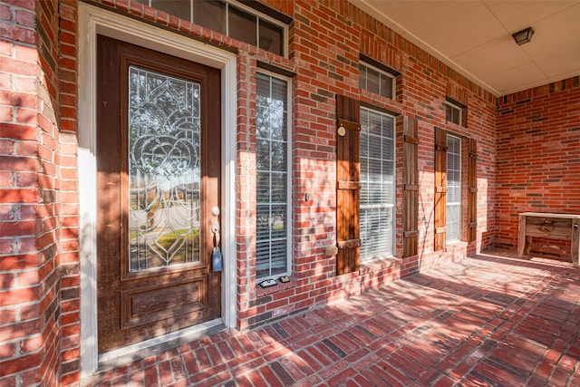 entrance to property with brick siding and a porch