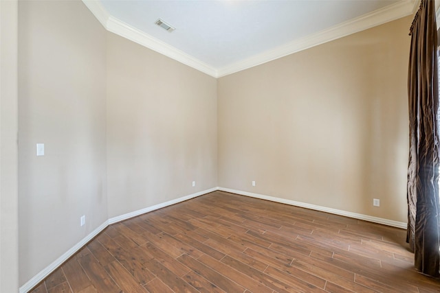 empty room featuring ornamental molding, visible vents, dark wood finished floors, and baseboards