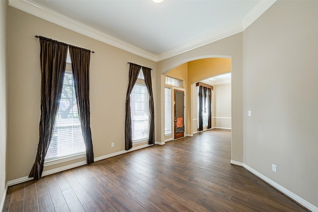 spare room featuring ornamental molding, arched walkways, dark wood-style flooring, and baseboards