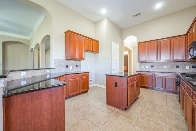 kitchen with a center island, visible vents, dark stone countertops, and light tile patterned flooring