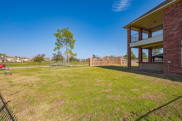 view of yard with a balcony and fence