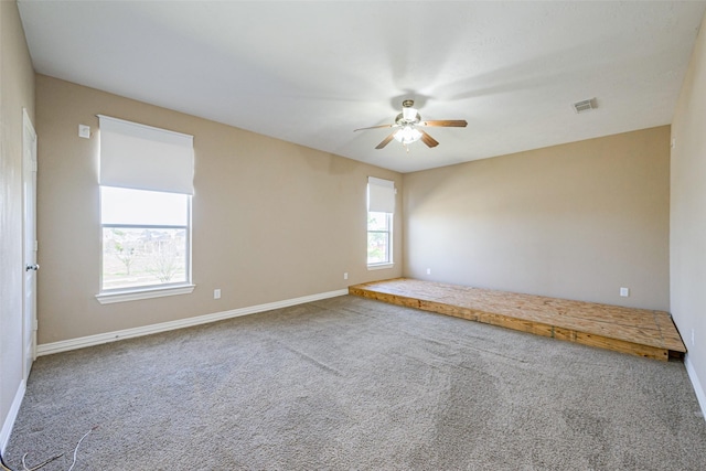 carpeted spare room with ceiling fan, visible vents, and baseboards