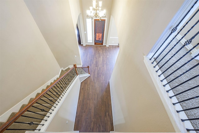 staircase with a chandelier, baseboards, and wood finished floors