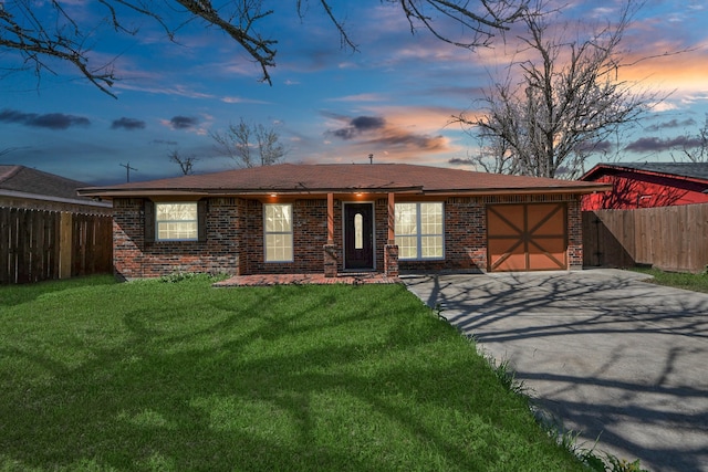 single story home featuring brick siding, an attached garage, fence, driveway, and a front lawn