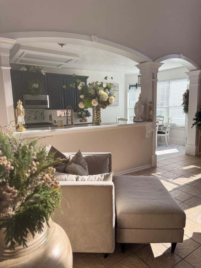 living room with arched walkways, baseboards, and ornate columns