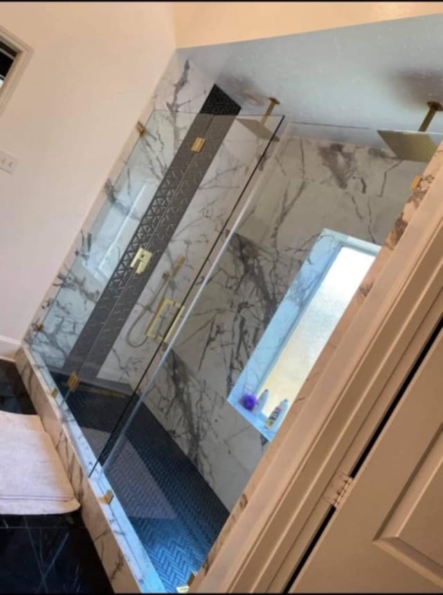 interior details featuring a marble finish shower