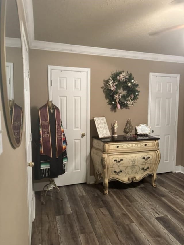 hall with dark wood-type flooring and ornamental molding