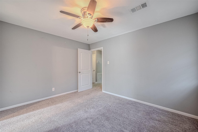 carpeted empty room featuring baseboards, visible vents, and a ceiling fan