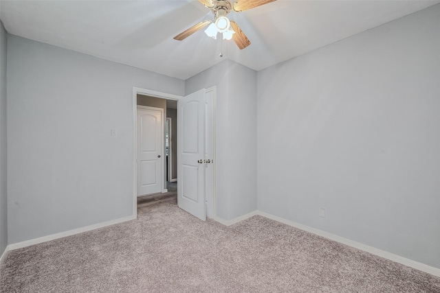 carpeted spare room with ceiling fan and baseboards