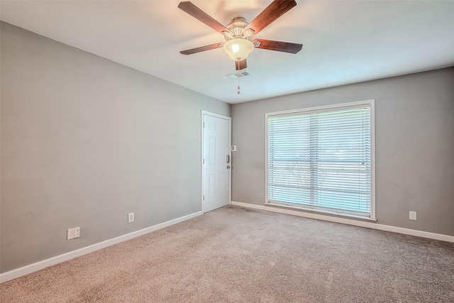 carpeted empty room featuring a ceiling fan, visible vents, and baseboards