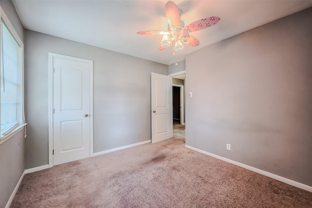 unfurnished bedroom featuring carpet floors, baseboards, and a ceiling fan