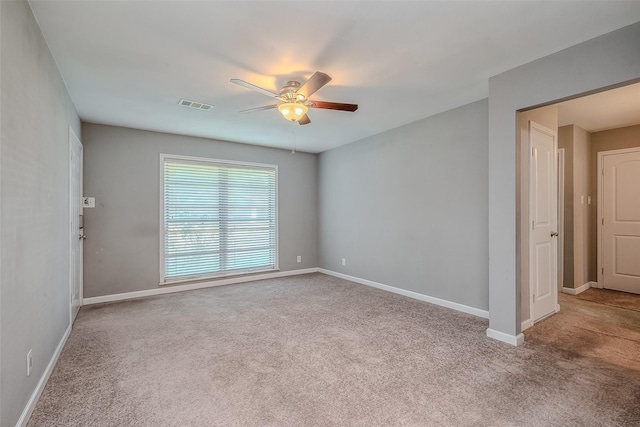 unfurnished room with carpet floors, visible vents, baseboards, and a ceiling fan