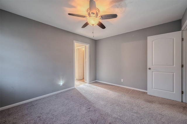 spare room featuring baseboards, a ceiling fan, and light colored carpet