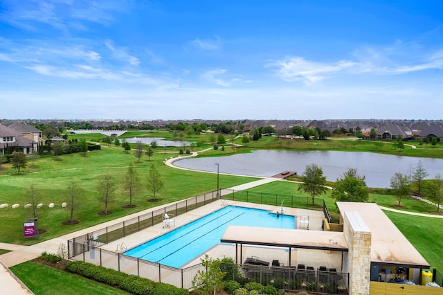 pool featuring a yard, a patio area, a water view, and fence